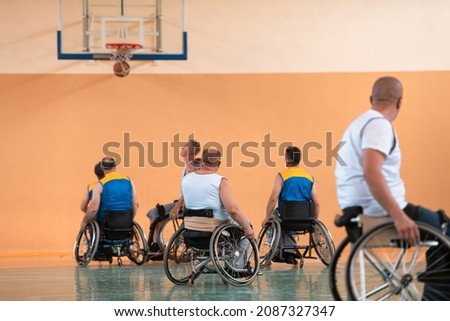 A photo of persons with a disability in wheelchairs playing a match in a sports gym hall. Concept sport for persons with a disability. Selective focus 