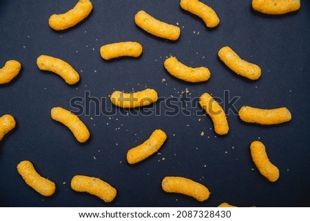 Cheese puffs laid on black background to a nice pattern