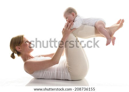 Young mother makes with her 6 month old daughter Rueckbildungsgymnastik, isolated against white background. Mama is down and has her baby lying on their lower legs.