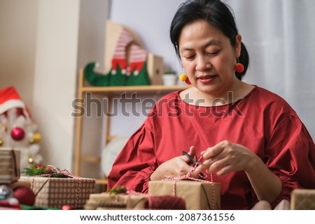 woman making Christmas handmade gift box with brown paper warpping with xmas decor on wood table Royalty-Free Stock Photo #2087361556