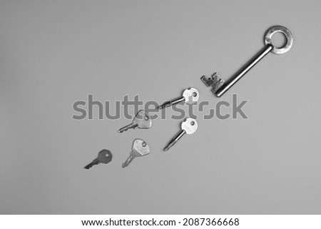 Door metal keys of different shapes on a gray background, top view. Monochrome image. Flat lay concept.