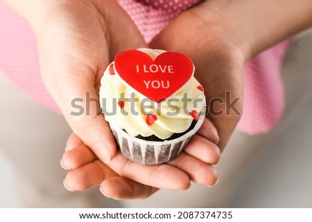 Girl holding heart shaped cake with the inscription I Love You. Cupcake in the shape of Heart, close up