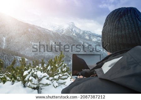 Man working with laptop on the top of mountain with beautiful landscape on background. High quality photo