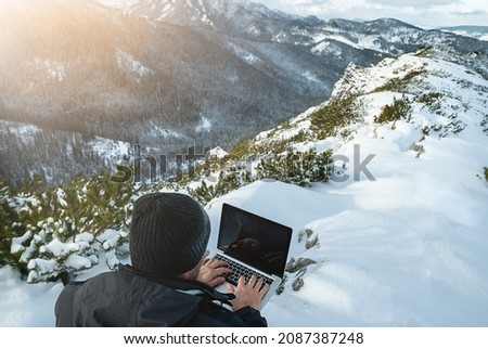 Man working with laptop on the top of mountain with beautiful landscape on background. High quality photo