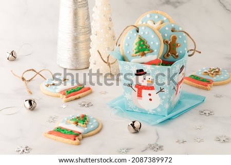 A gift box of homemade snow globe cookies with more cookies all around.