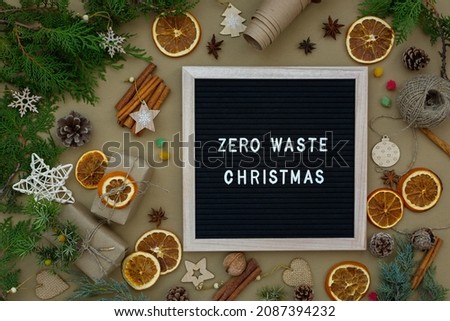 Zero waste Christmas concept. Natural materials wood, paper, fir branches, cones, nuts, dried citrus fruits, cinnamon. Frame with an inscription. Eco-greeting card, muted natural shades. New Year 2022