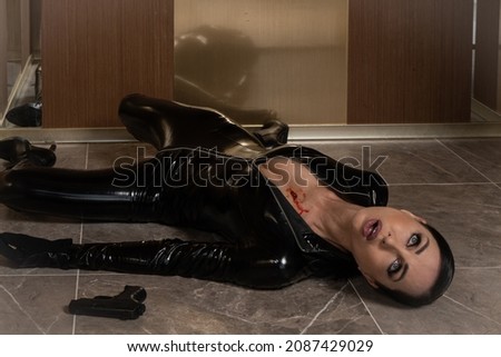 Hit woman. Woman in a latex suit killed in gunfire shot in the chest

 Royalty-Free Stock Photo #2087429029
