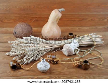 Wheat concept on a wooden background. Still-life. A bunch of wheat. Pumpkin. Coconut. Ceramic jugs. On a wooden background. 