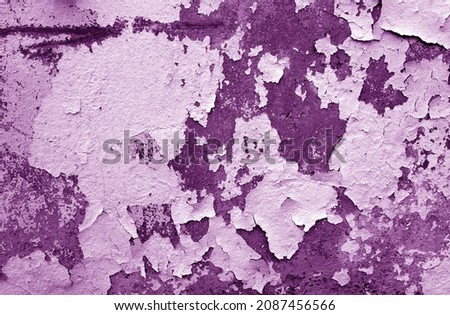 Cement wall with peeling paint and plaster in purple tone. Grungy and weathered background. 
