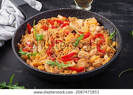 Heart-shaped pasta  in tomato sauce with chicken and sweet pepper with arugula. Background, texture