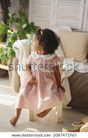a dark-skinned girl is sitting on a wooden chair at home. the concept of environmental friendliness and children's goods. high-quality photography