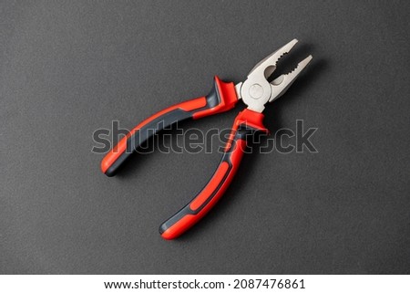 Pliers in red and black colored on a black background with blank text space Royalty-Free Stock Photo #2087476861