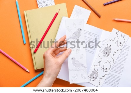 Female hand with cute bookmarks and books on color background