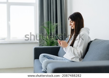 Young Woman use of smartphone at home while laying on sofa