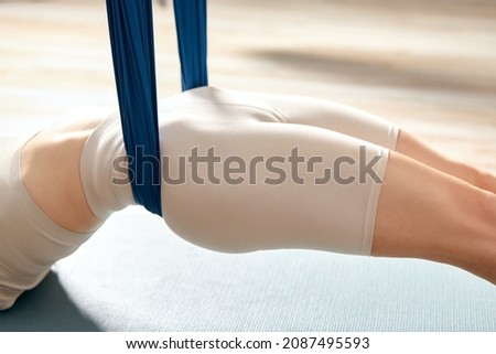 Closeup of young woman legs using hammock and doing aerial yoga exercises.