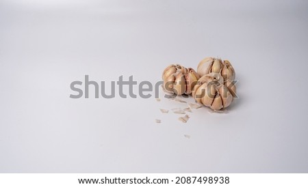 A photo of garlic that looks like it has been placed on a white background. Garlic is a pungent member of the Allium genus. It is widely used in cooking.