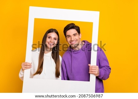 Portrait of two persons hold paper photo frame toothy smile look camera isolated on yellow color background