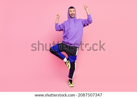 Full size photo of funky millennial brunet guy point up wear hoodie pants shoes isolated on pink color background