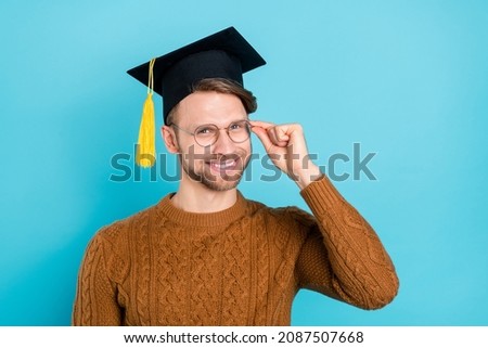 Photo of confident pretty guy dressed knit sweater academic headwear arm spectacles smiling isolated blue color background