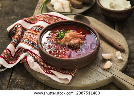 Borscht - Traditional Ukrainian dish.  Vegetable soup made from beets, potatoes, cereals and boiled meat, and  slices of rye bread in a ceramic bowl on a wooden kitchen table. Russian  food cuisine Royalty-Free Stock Photo #2087511400