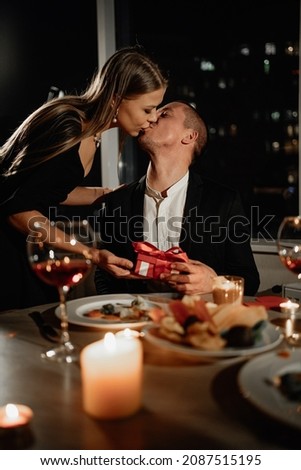 Passionate kiss on a date man and woman, Valentine's Day festive dinner for two, a gift to a loved one, wedding anniversary husband and wife in the evening at home