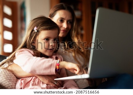 Cheerful little girl using laptop. Beautiful girl watching cartoon with mom	
