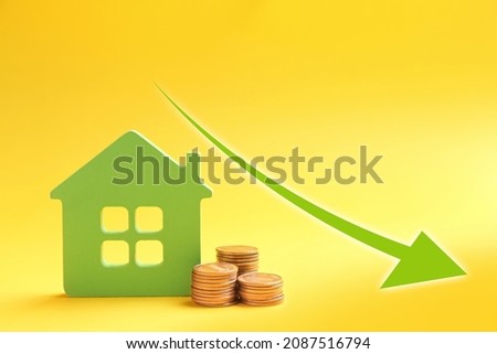 Mortgage concept. House model and coins on yellow background 