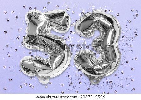 Silver foil balloon number, digit fifty three on a lilac background with sequins. Birthday greeting card with inscription 53. Top view. Numerical digit. Celebration event, template.
