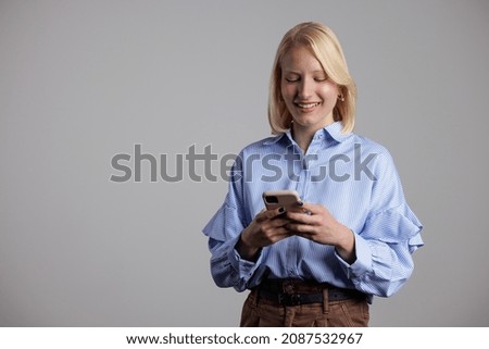 Attractive young woman, using her phone while taking a picture.