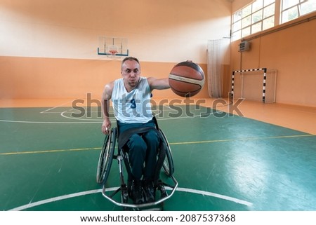 A photo of person with a disability playing basketball in a modern sports arena. The concept of sport for people with disabilities. Selective focus 