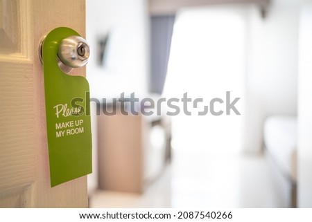 Please make up my room. Maid cleaning the room with please make up my room sign on the door. 