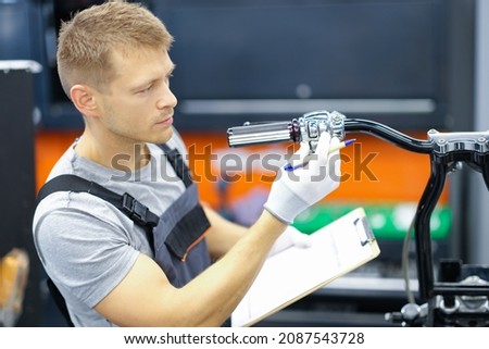 Young locksmith conducts diagnostics of motorcycle in service center