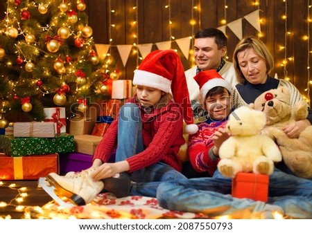 Happy family posing in new year or christmas decoration. Children and parents. Holiday lights and gifts, Christmas tree decorated with toys.
