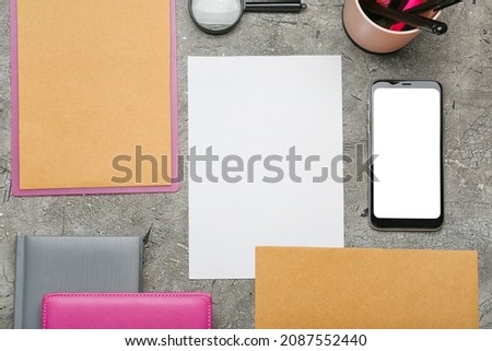 Composition with blank paper sheet, mobile phone and stationary on dark background