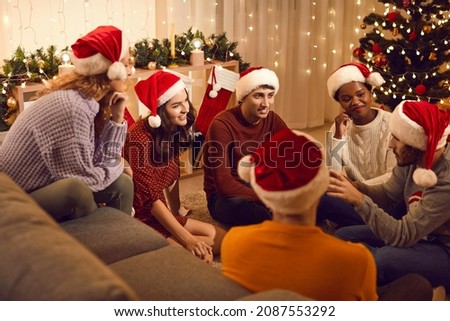 Happy diverse multiracial friends in Santa hats have fun chat celebrating Christmas together. Smiling international people gather at home enjoy New Year party celebration. Friendship, diversity.