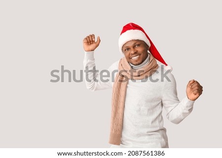 African-American man in Santa hat on light background