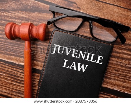 Selective focus.Gavel,glasses and notebook written with text JUVENILE LAW on a wooden background. Royalty-Free Stock Photo #2087573356