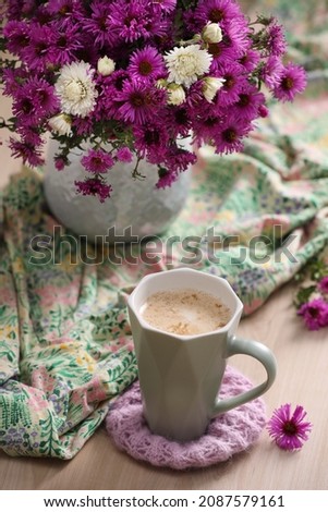 Cup of aromatic coffee, beautiful flowers and bright cloth on wooden table