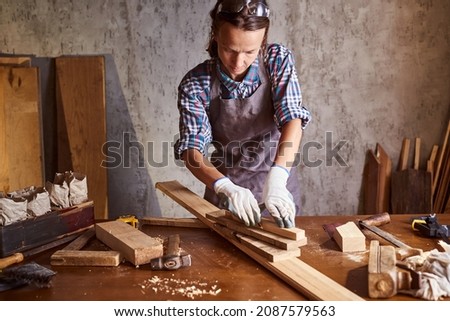 Business woman working as carpenter in a small carpentry workshop. Female carpenter working in carpentry shop with pencil drawing sign on plank. Girl professional high skill workman.