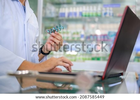 Young male pharmacist checking drugs in the pharmacy inventory using a computer at a pharmacy high quality photos