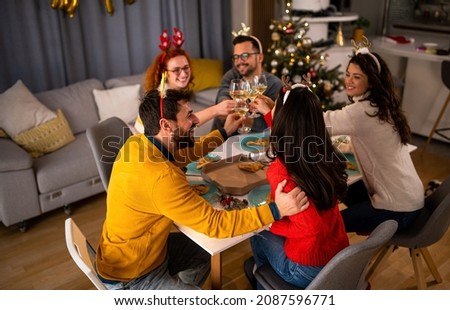 Young friends toast with champagne. A fun group of people at Christmas dinner.