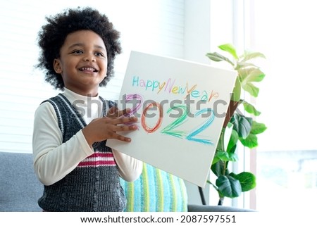 Dark-skinned boy enjoys showing someone a New Year's card., African boy are glad to present their art work, happy new year 2022