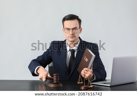 Male judge at table on grey background