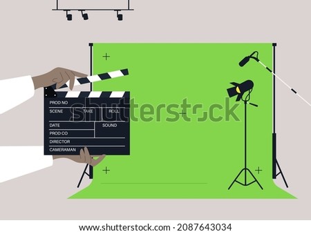 A movie set with a chroma key screen, lighting equipment, microphones, and a clapper board