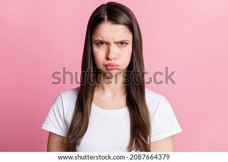 Portrait of attractive grumpy evil girl holding air in cheeks bad mood isolated over pink pastel color background