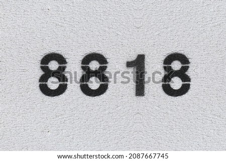 Black Number 8818 on the white wall. Spray paint. Number eight thousand eight hundred and eighteen.