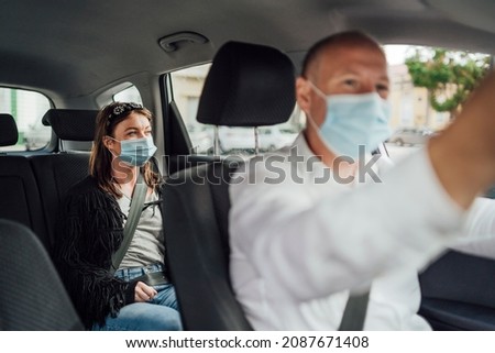 Taxi driver in a mask with a client on the back seat wearing mask Royalty-Free Stock Photo #2087671408