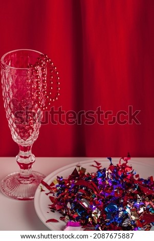 Table with New years still life party themed image of holiday decorations. Close up of the set decor for Christmas party on a table with a red cloth in the background. Vintage style holiday image. 