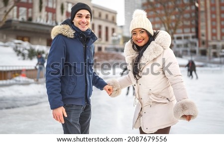 A couple ice skating outdoors on a winter day