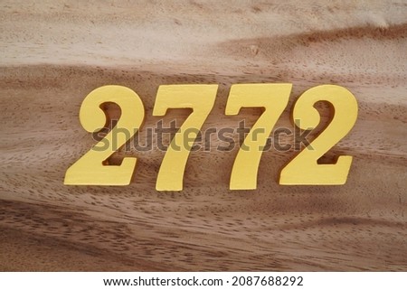 Golden Arabic numerals 2772 on a dark brown to white wood grain background.